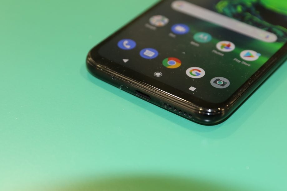 Bottome edge view of a black Motorola G8 Plus laid on a green table