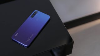 A blue Redmi Note 8T smartphone laid on a black table facing down, back panel view