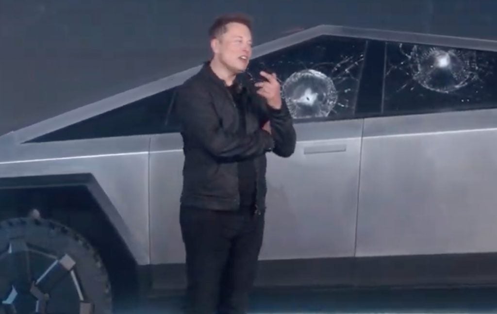 Elon Musk standing in front of a Tesla Cybertruck in black outfit