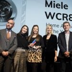 Three women receiving award from two men on stage, Miele WCR860 displayed on screen behind, Trusted Reviews Awards