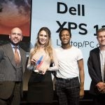 A man and a woman receiving award from two men on stage, Dell XPS displayed on screen behind, Trusted Reviews Awards