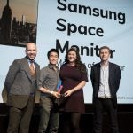 A man and a woman receiving award from two men on stage, Samsung Space monitor displayed on screen behind, Trusted Reviews Awards