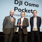 A man receiving award from two men on stage, DJI Osmo Pocket displayed on screen behind, Trusted Reviews Awards
