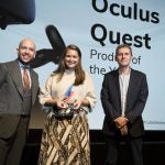 A woman receiving award from two men on stage, Oculus Quest displayed on screen behind, Trusted Reviews Awards