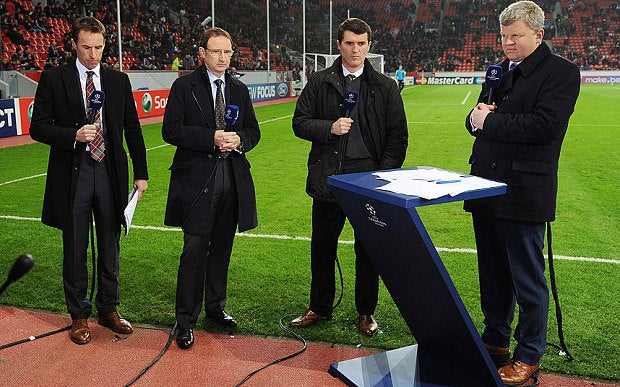 Four men in black outfit standing on the edge of a Football field in a stadium, picture from Adrian Chiles Champions league