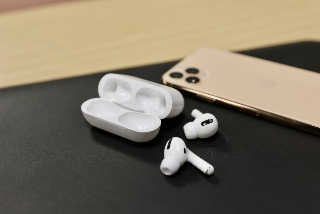 AirPods Pro rests next to the case and iPhone on a black table