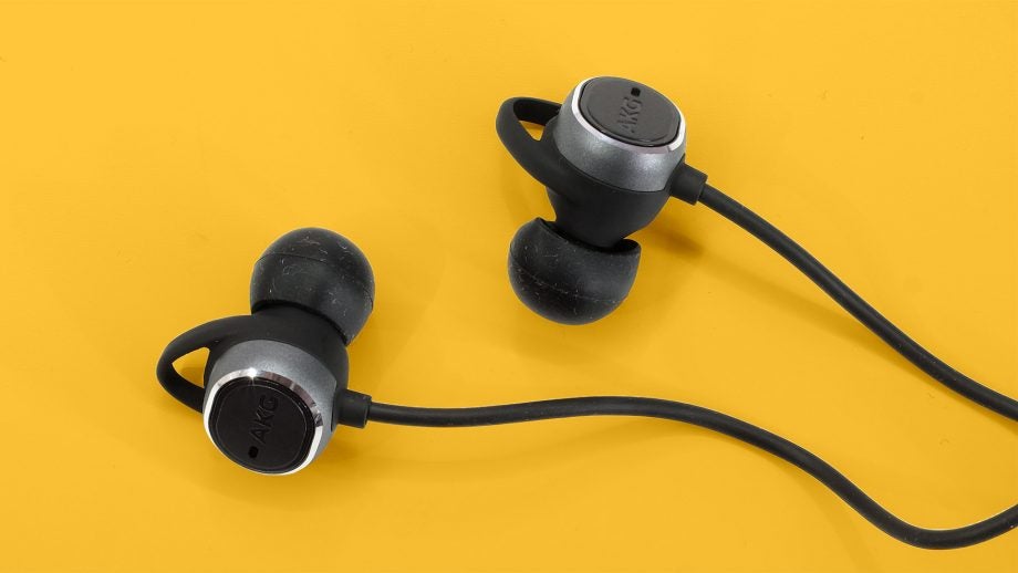 Close up view of earbuds of AKG N200NC wireless earphones kept on a yellow table