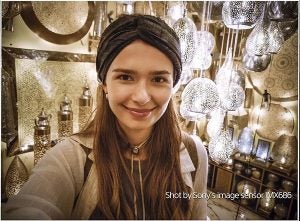 Selfie of a woman in a lamp shop with shot by Sony's image sensor IMX686 written on bottom right