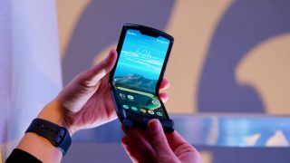 A Motorola Razr held in hand in half folded state displaying homescreen