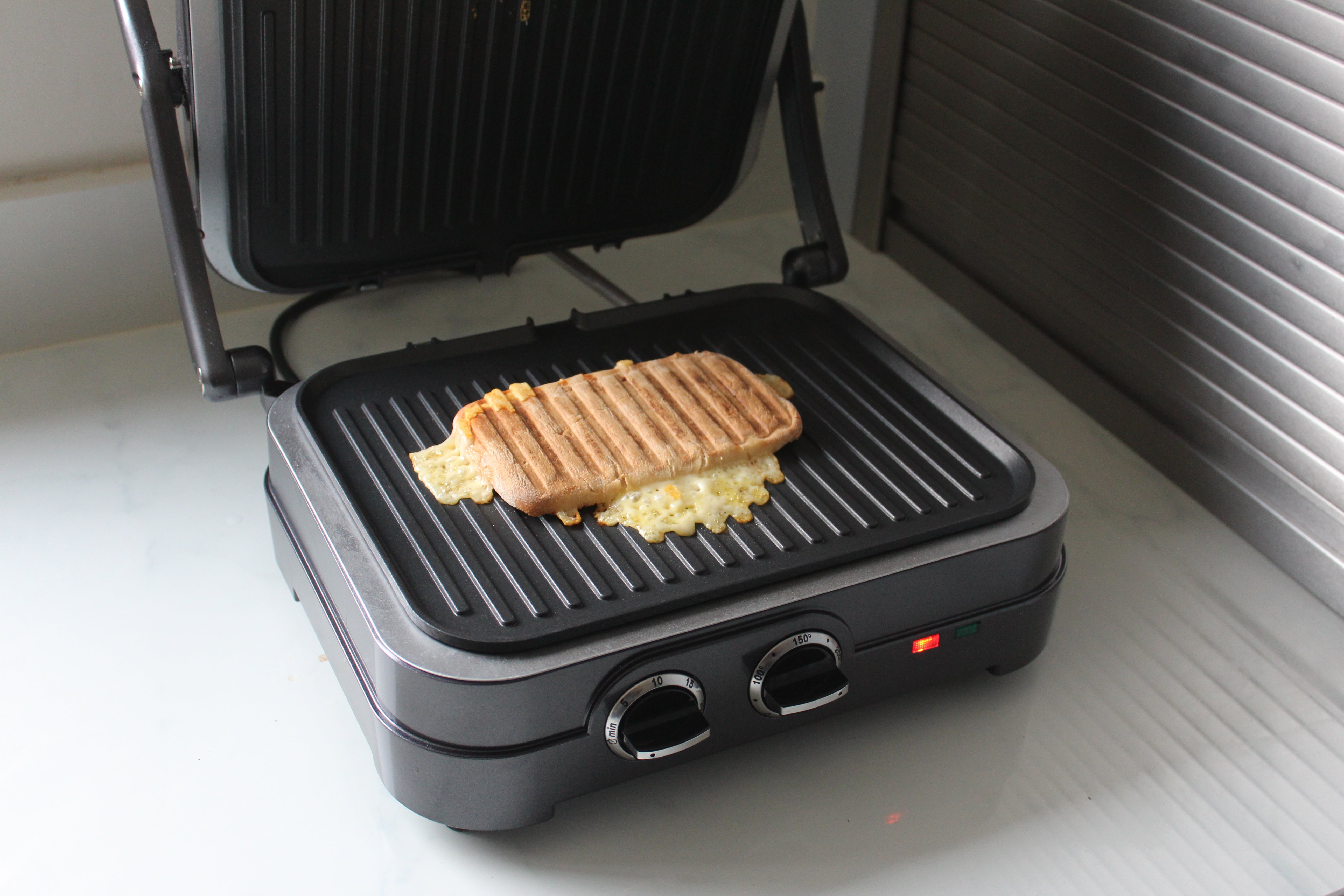 Cuisinart Griddle & Grill PaniniA picture of gray-black Cuisinart GR47BU Griddle-Grill with sandwich being grilled on it