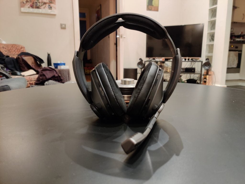 A picture of black headphones with mic standing on a black table