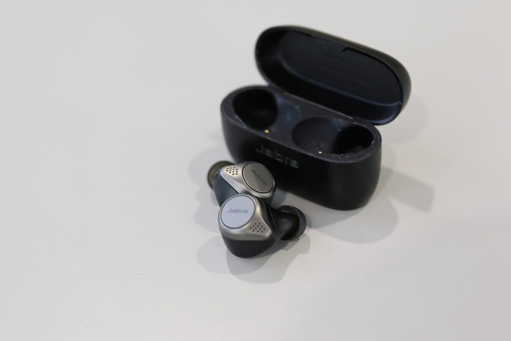 Jabra Elite 75TA picture of silver-black Jabra Elite 75T earbuds with it's case behind kept on a table