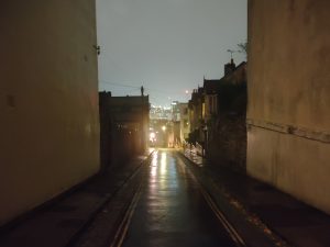 A picture of a street taken at night with building on either sides and stairs far ahead, with night mode off