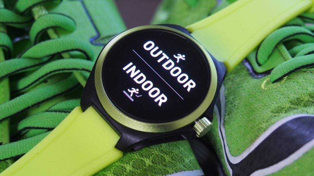 Picture of a green-black Puma smartwatch kept on shoe displaying outdoor and indoor's screen