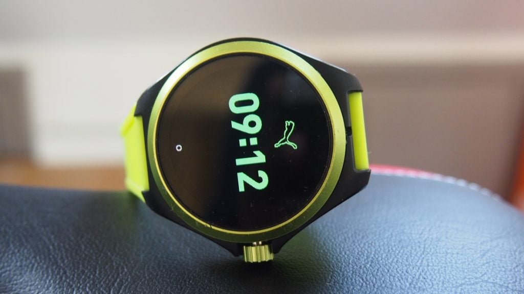 Picture of a green-black Puma smartwatch kept on a cushion displaying time