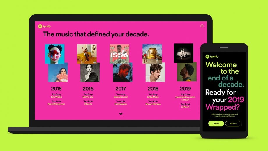 A black smartphone and a laptop standing on green background displaying musics that defined your decade