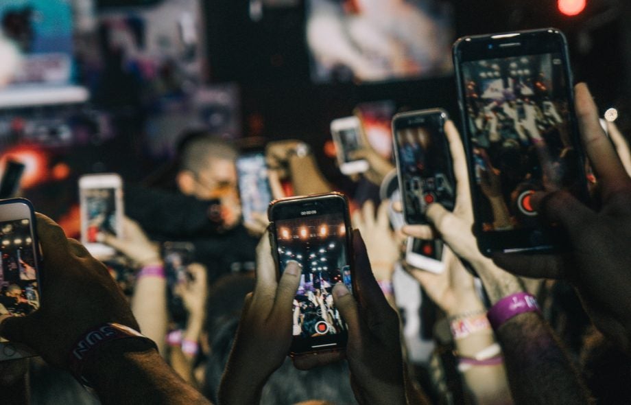 Picture from a crowd with most of the people holding their phones up and recording