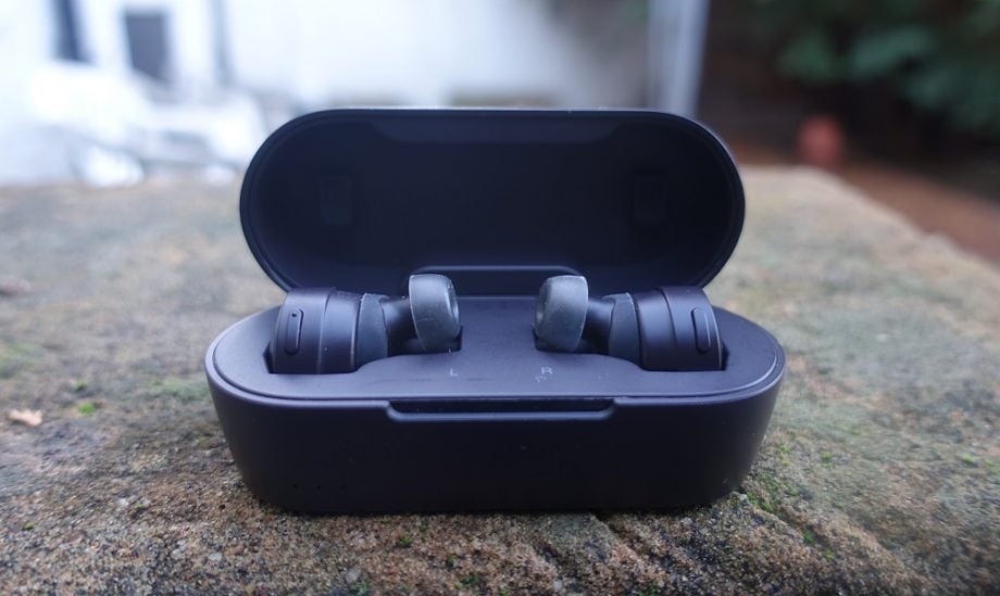 Picture of black Audio Technica CKS5TW earbuds resting in it's case on ground
