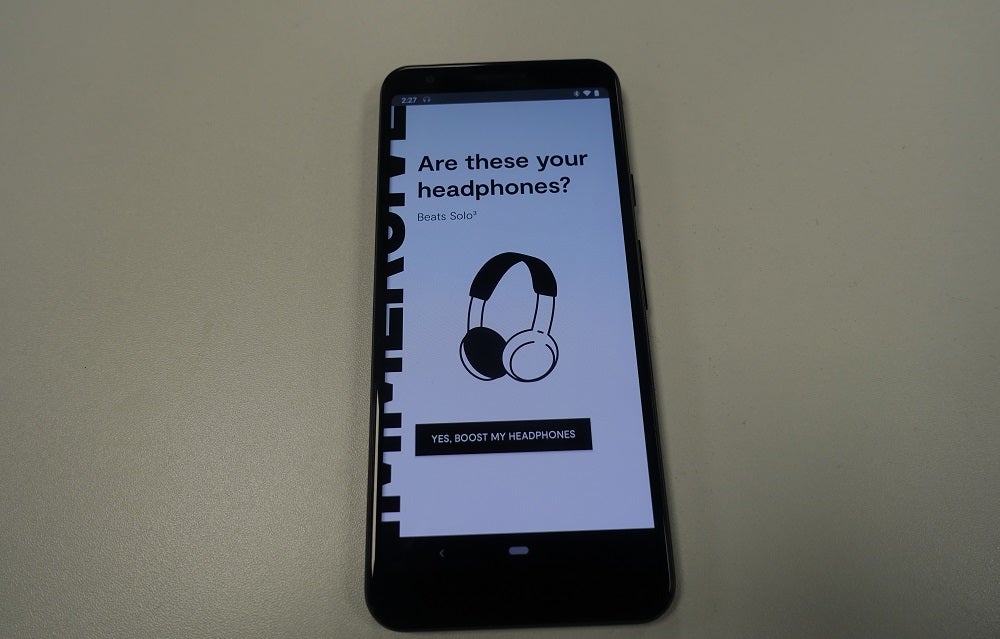 A black smartphone kept on a table displaying are these your headphones screen on Dirac mobile app
