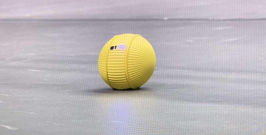 A picture of a yellow ball kept on ground with three lights and two ports on it