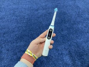 A picture of a white Oral B brush held in hand with a tiny screen at it's center