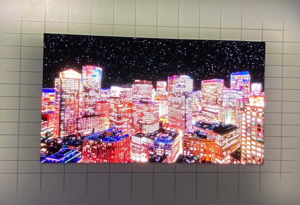 A Samsung 75 Micro LED TV mounted to a wall displaying a picture of a city