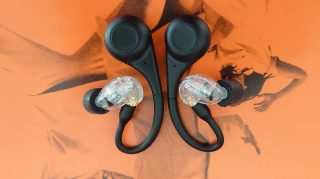View from top of black Shure Aonic 215 earbuds kept on an orange background