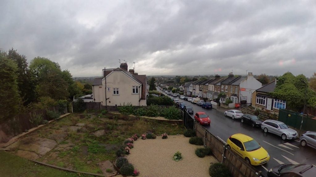 View from top of a street similar houses on either sides and cars parked on the front