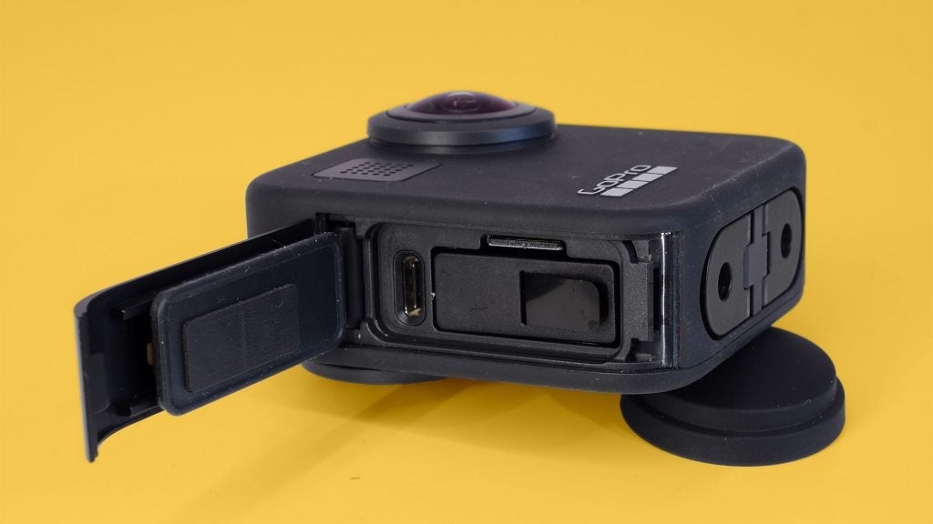 Right side edge view of a gray GoPro Max camera kept on a yellow background