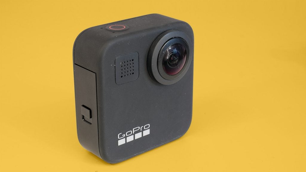 Left angled view of a gray GoPro Max camera standin on a yellow background
