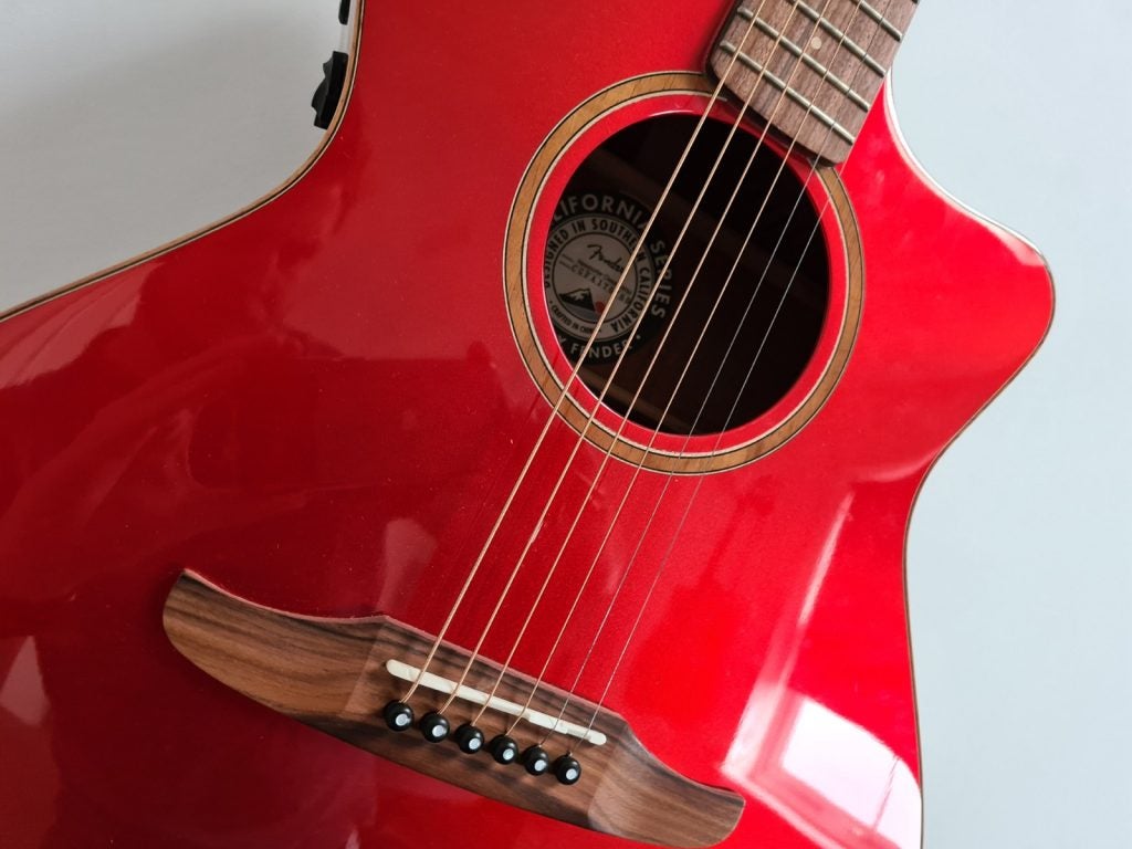 Picture of a red guitar standing against a white wall
