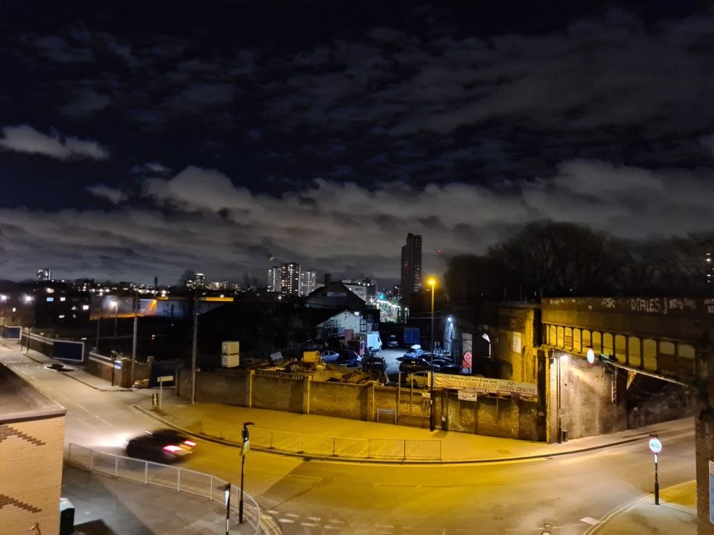 View from top of a street with underbridge on the right and houses and warehouses aroundView from top of a street at night with underbridge on the right and houses and warehouses aroundPicture of a red guitar standing against a white wall