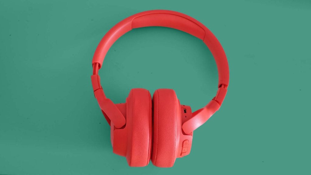 View from top of red JBL Tune 750BTNC headphones kept on a green background