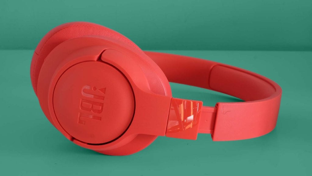 Side view of red JBL Tune 750BTNC headphones kept on a green background