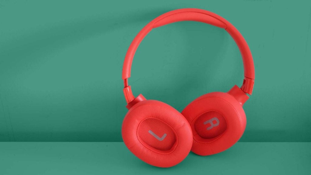 Red JBL Tune 750BTNC headphones standing on a green background, earcups inside view