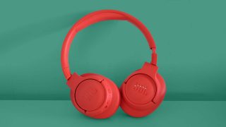 Red JBL Tune 750BTNC headphones standing on a green background