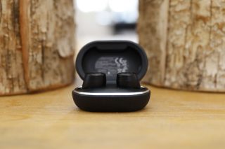 Black Beoplay E8 3rd Gen earbuds resting in it's case on a table