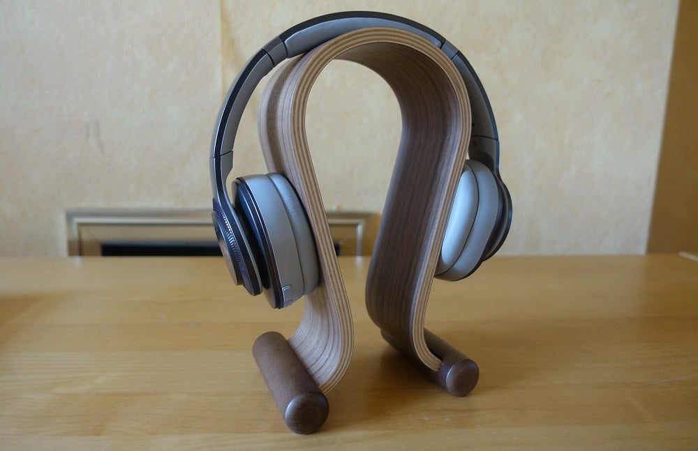 Picture of blue-silver and black Cleer Flow II headphones placed on a headphone stand on a table