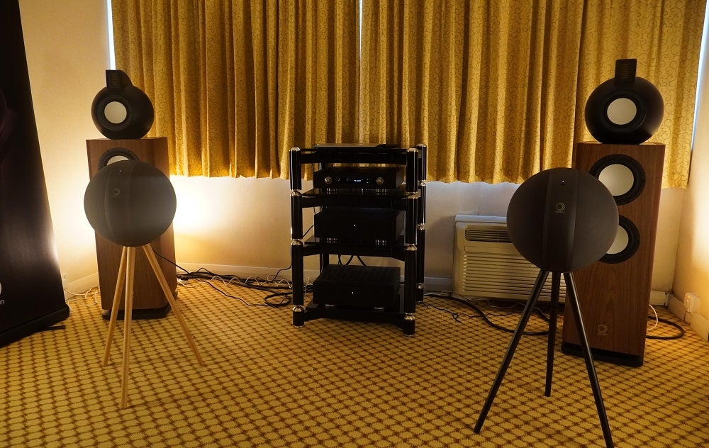 Two black round Elipson W35 speakers standing on stand in a room