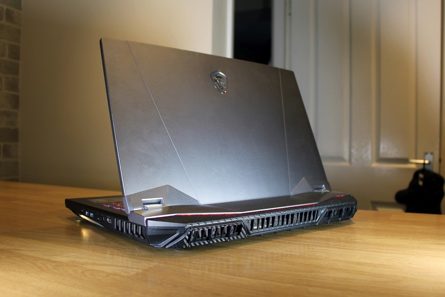 MSI GT76 Titan DT 9SGBack left view of a gray-black MSI GT76 laptop standing on a wooden table