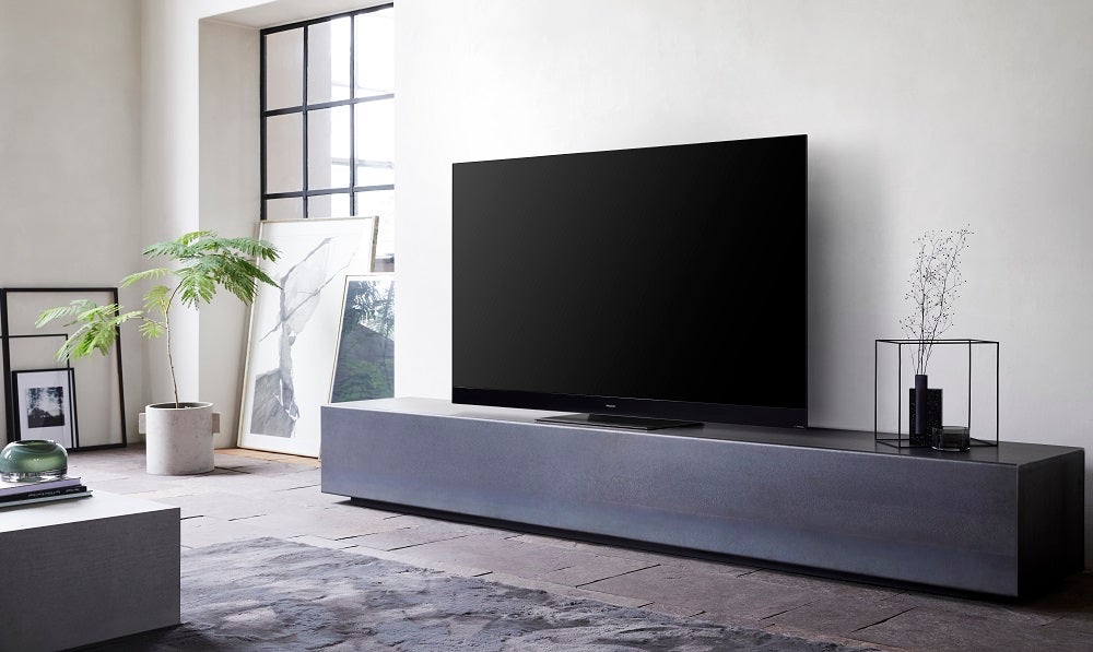 A black Panasonic 65HZ2000E TV standing on a black table in a living room