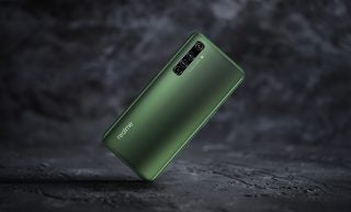 A dark green Realme smartphone standing on black background facing back, back panel view
