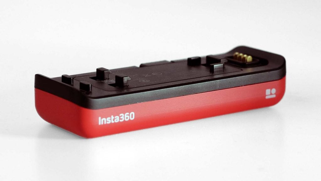 Close up image of red-black Insta 360's battery kept on a white background