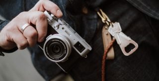 A silver-black Fujifilm X100V camera held in hand