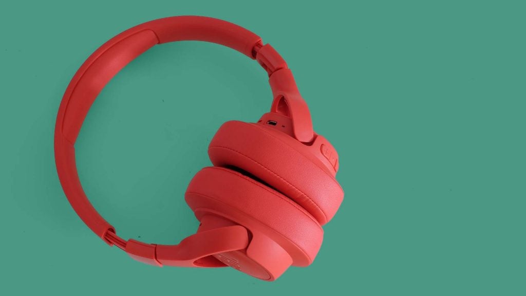 A picture of red JBL Tune 750BTNC headphones kept on a green background