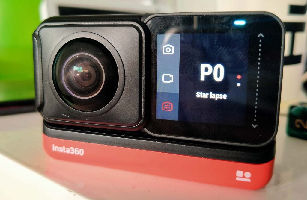 Close up image of black-red Insta 360 One R camera standing on a white table