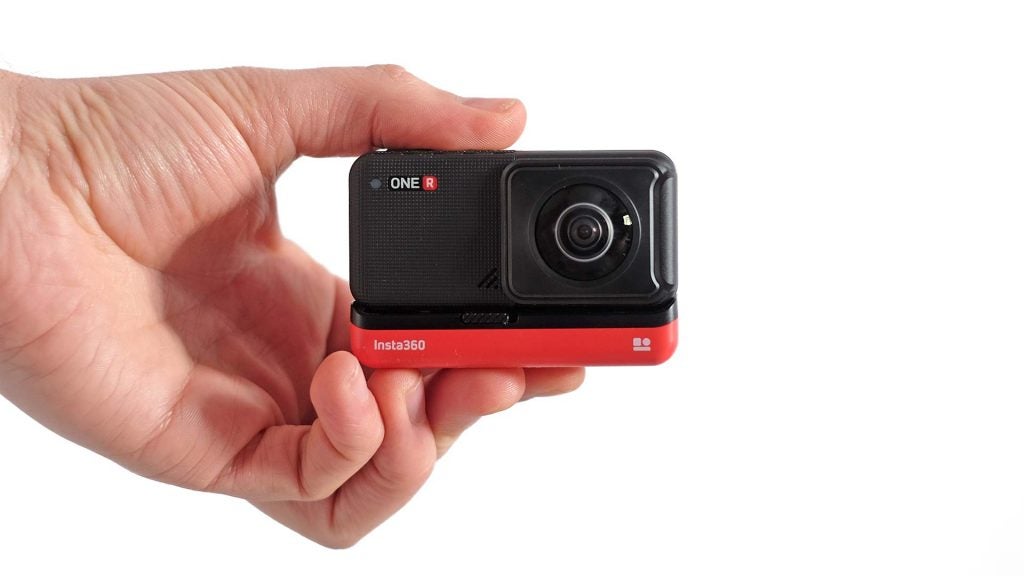 A black-red Insta 360 One R camera held in hand