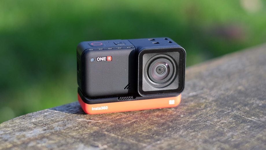 A black-red Insta 360 One R camera standing on wooden surface