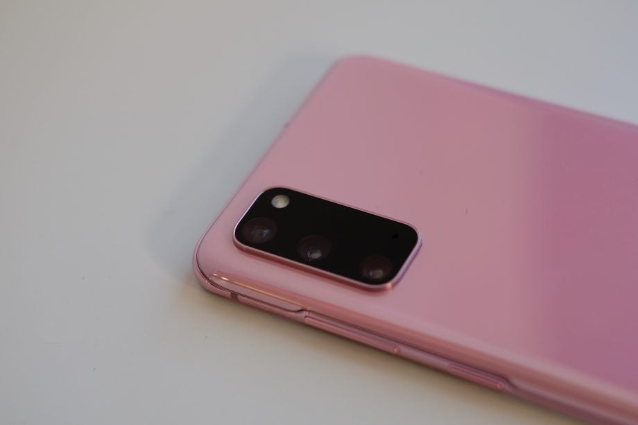 A pink Samsung Galaxy S20 kept upside down on a table, top half back panel view