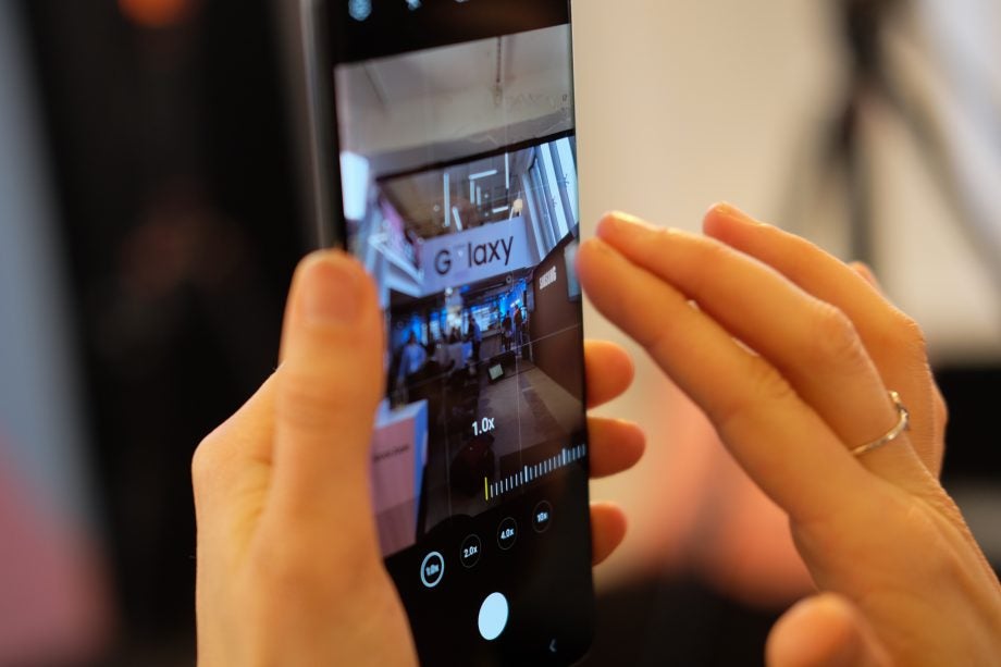 A Samsung Galaxy S20 Ultra held in hand with zoom in bar displayed on camera app